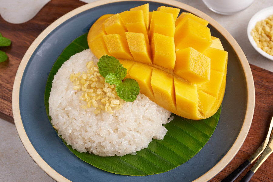 Ripe mango and sticky rice with coconut milk in a plate on stone